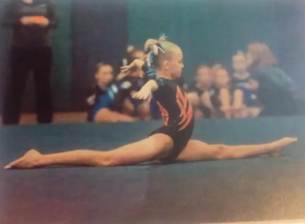 Young Bea performing splits at a gymnastics competition.