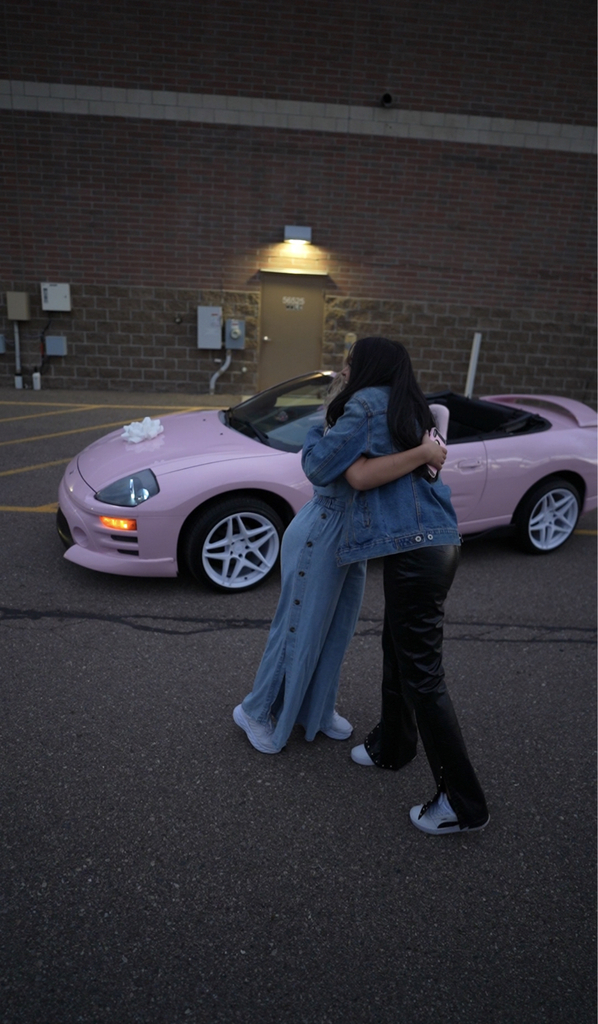 Christina Roki hugging someone in front of a pink Mitsubishi Eclipse.